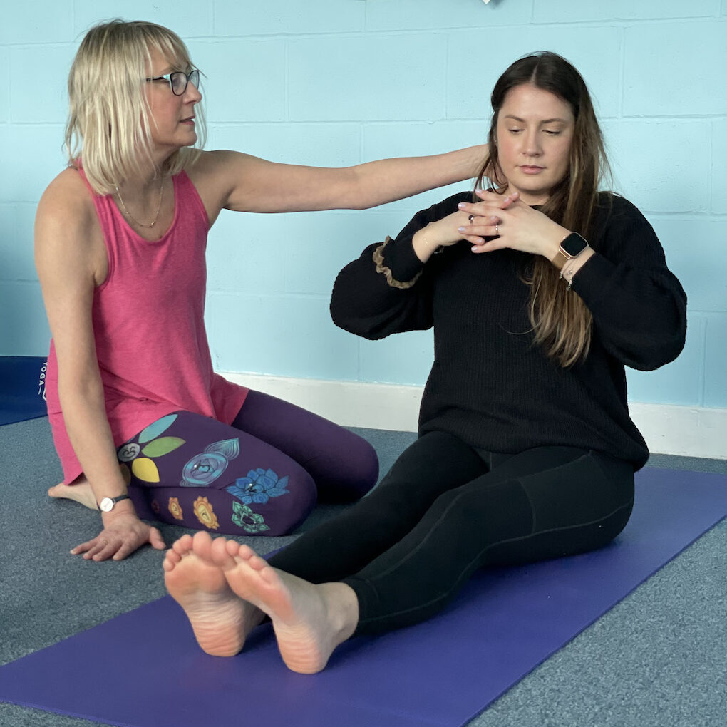 Yoga teacher helping a young lady keep a good posture